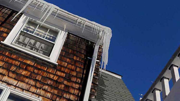 Gutters of a house covered in icicles and ice dams.