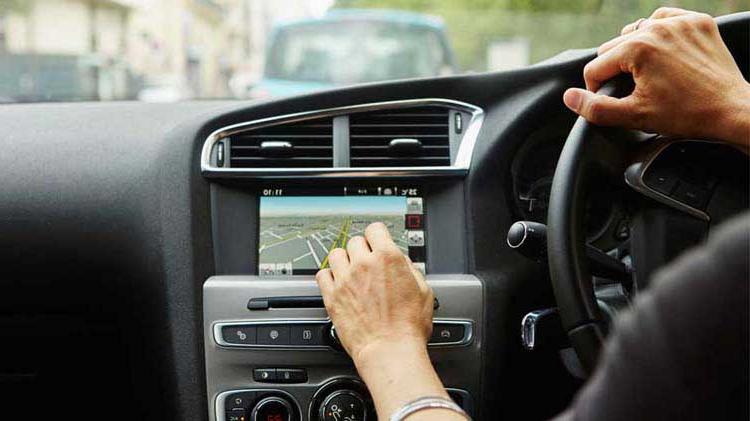 车里的人, one h和 on the steering wheel 和 one interacting with an onboard telematics device.