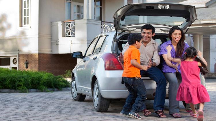 家庭 of four sitting on the back of their van.