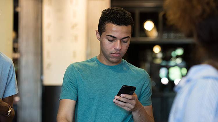 Young man looking at phone after receiving a spoofed call.