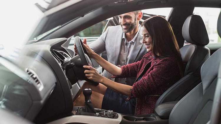 A young woman checking out a new car. 