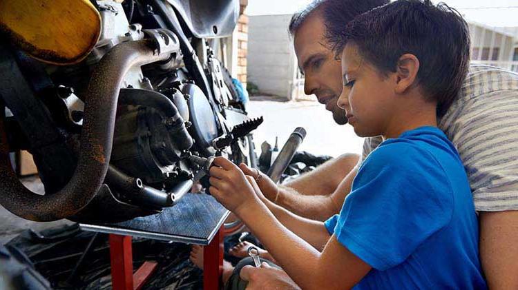 Father and child preparing to store a motorcycle