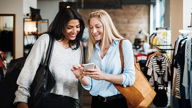 Woman showing her friend how to organize her phone apps in folders