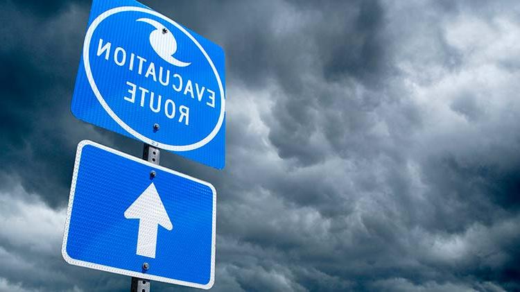 Hurricane evacuation route sign with storm clouds.