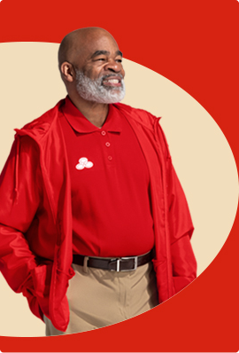 A bearded 州立农场代理 in red shirt and red pullover jacket smiles.