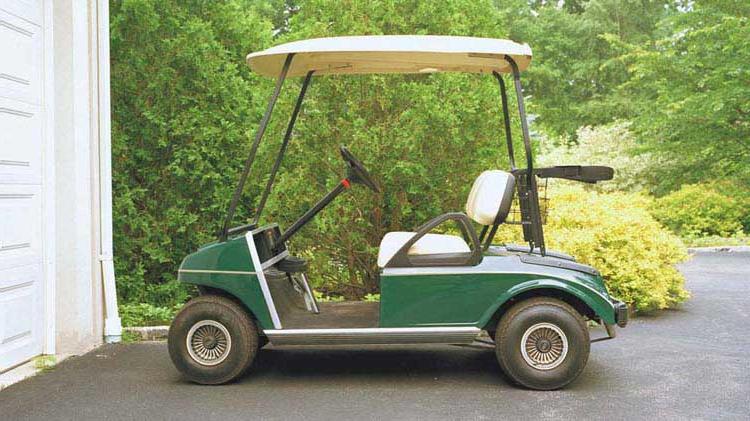 A golf cart is parked on a driveway.