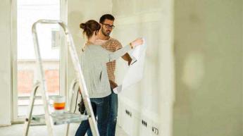 A couple re-plasters an interior wall